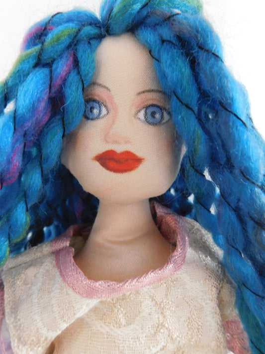 handmade fabric doll with light pink top, floral skirt and blue hair made of wool