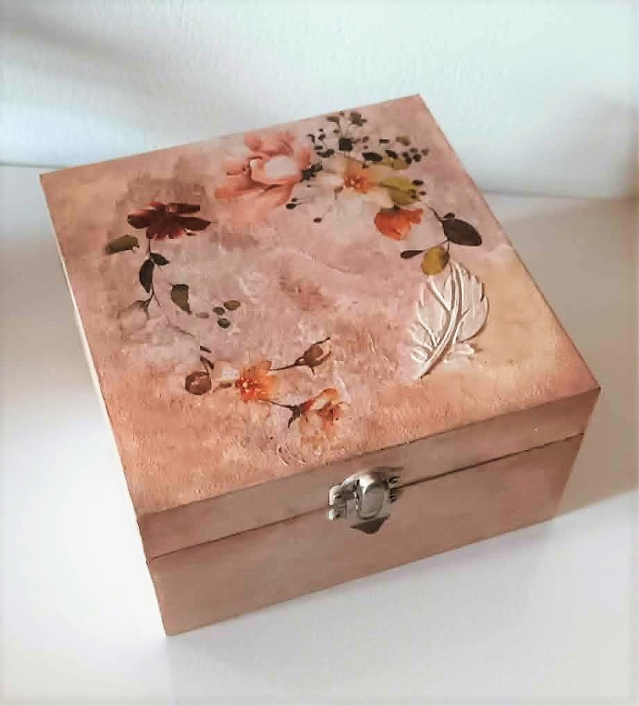 Wooden box with floral design and metallic clasp on a white background