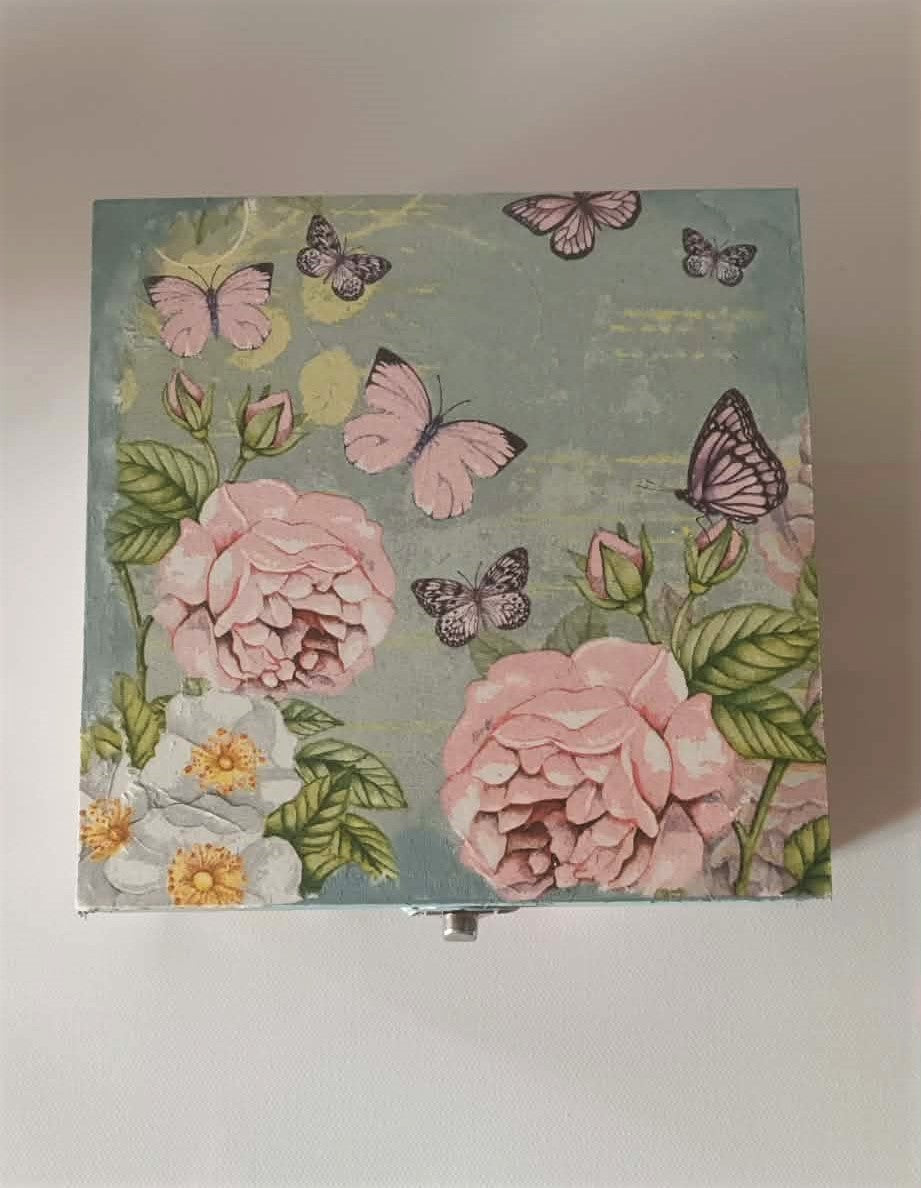 Floral and butterfly design on a rectangular box with a light background