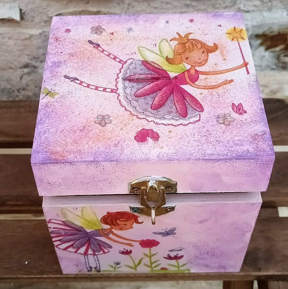 Pink money box with fairy design on a wooden surface with a lock and keys