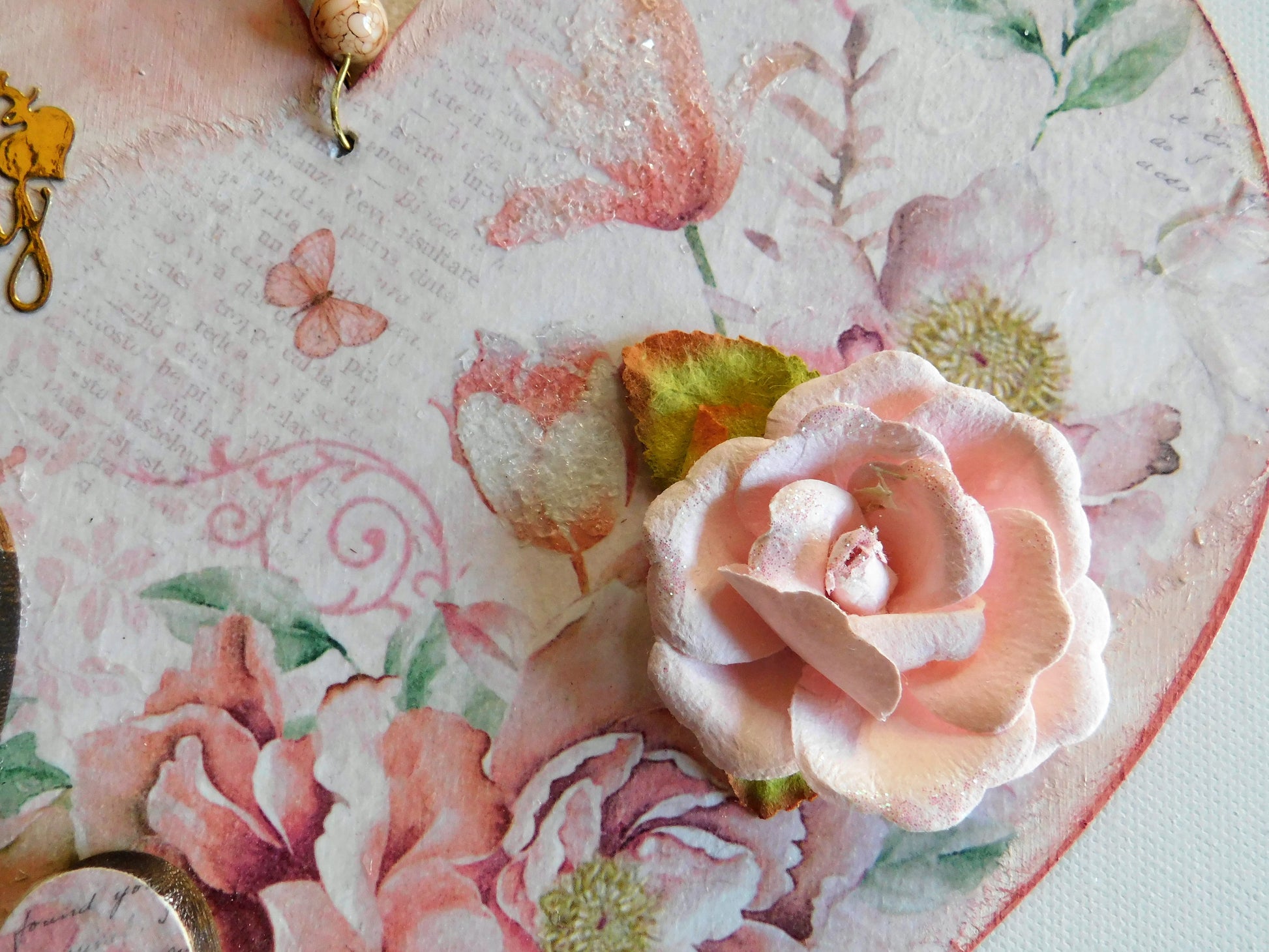 Close-up of a decorative item with pink flowers and green leaves on a textured surface.