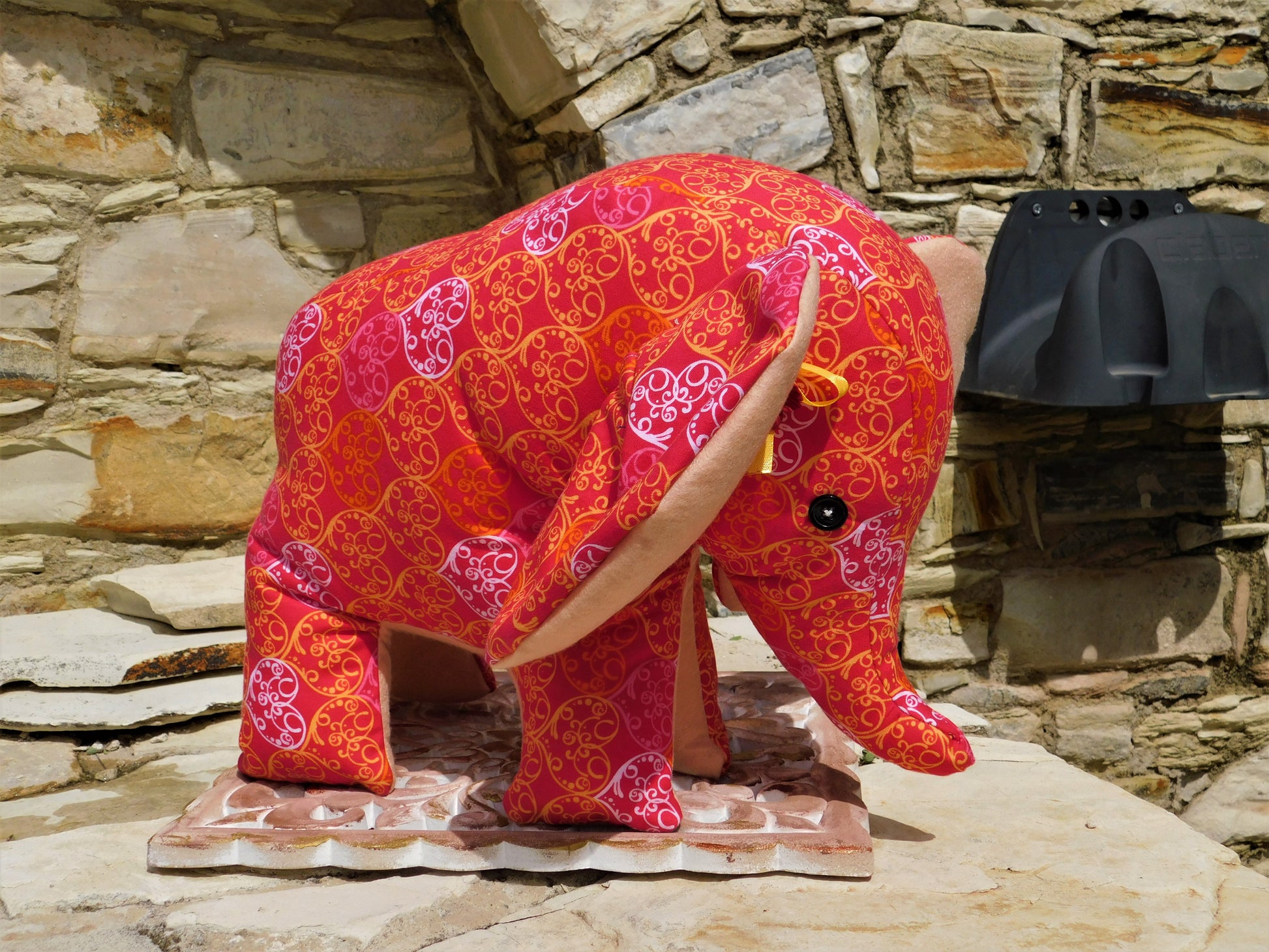 Decorative elephant with red and pink patterns on a stone surface