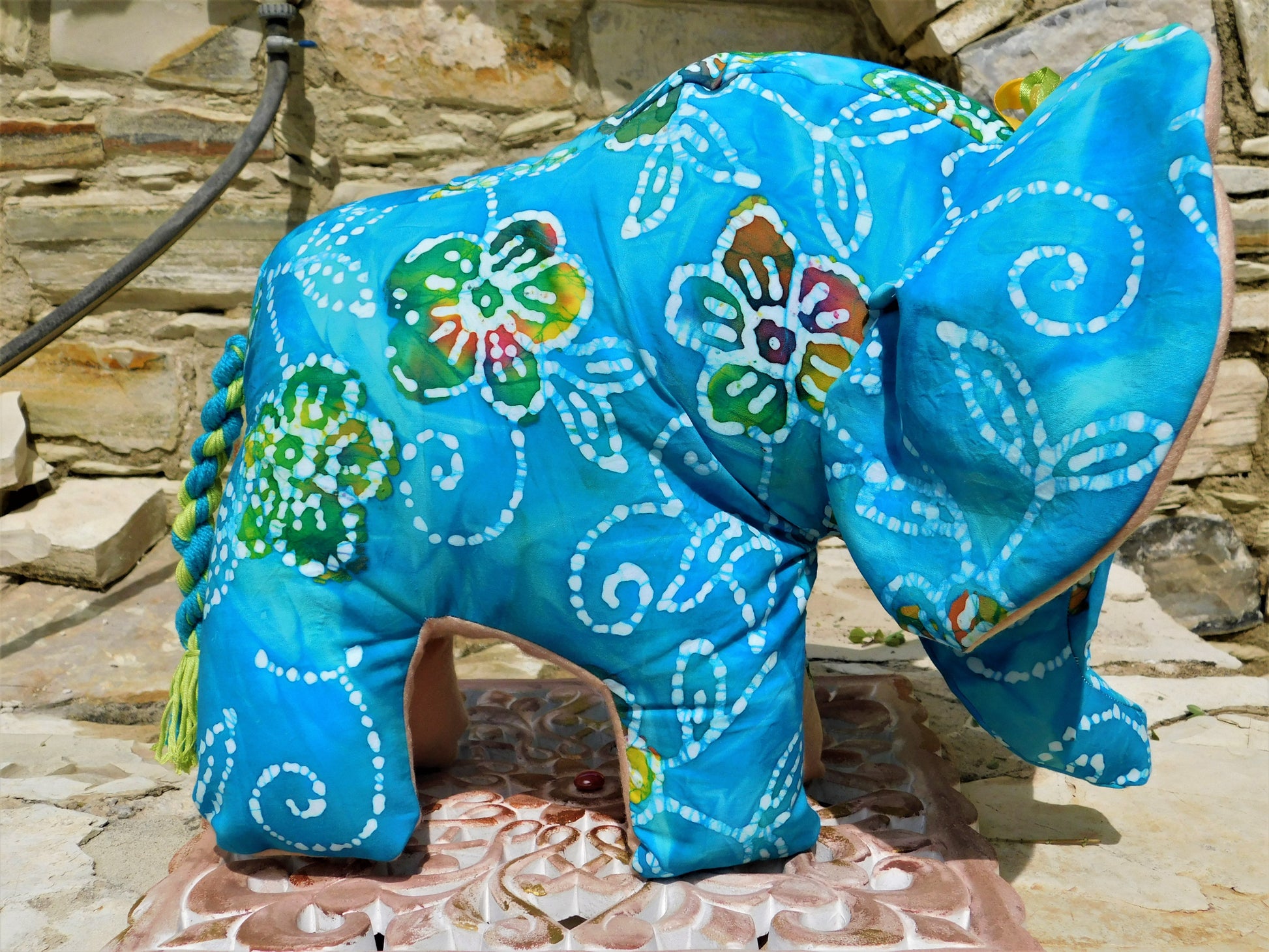 Decorative elephant figurine with blue floral patterns on a stone surface