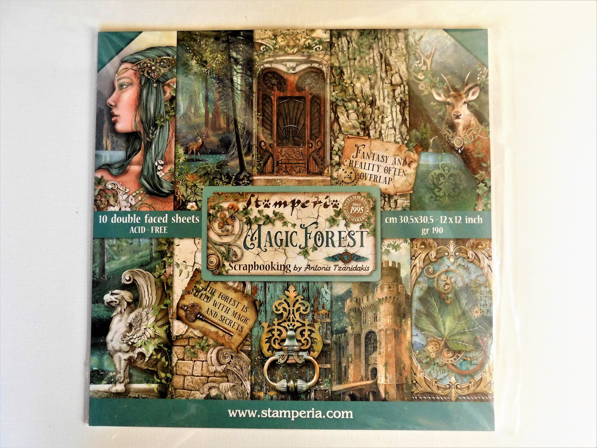 A packaged sheet set of decorative scrapbooking paper sheets titled 'Magic Forest' by Antonis Tzanidakis, featuring a collage of woodland-themed designs including a woman's profile, a deer, a tree trunk, a gate, and vintage-style text panels on a white background.