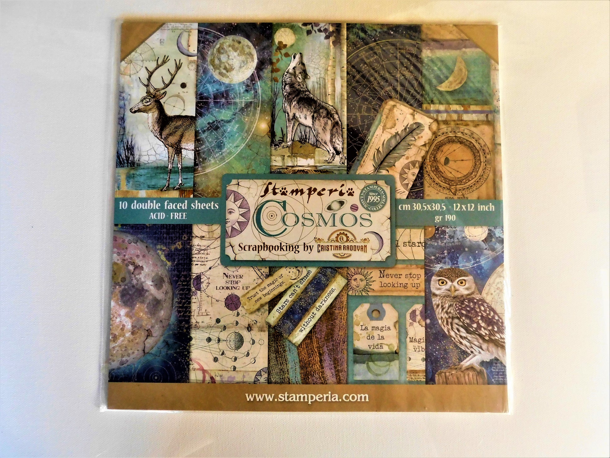 A square scrapbooking paper sheet set titled 'Stamperia Cosmos' with a collage of vintage-style illustrated panels, including a deer, wolf, owl, moon, compass, and script elements.