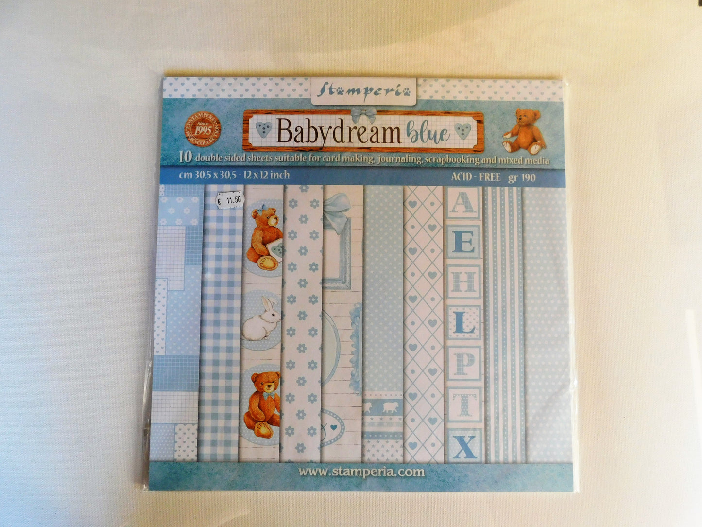 A package of Stamperia Babydream Blue scrapbooking paper, featuring 10 double-sided sheets with various blue patterns, stripes, and teddy bear illustrations.