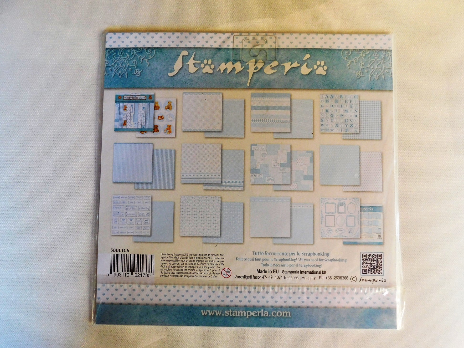 A packaged paper craft scrapbook pad by Stamperia, showing various patterned and solid cardstock sheets on the back cover.