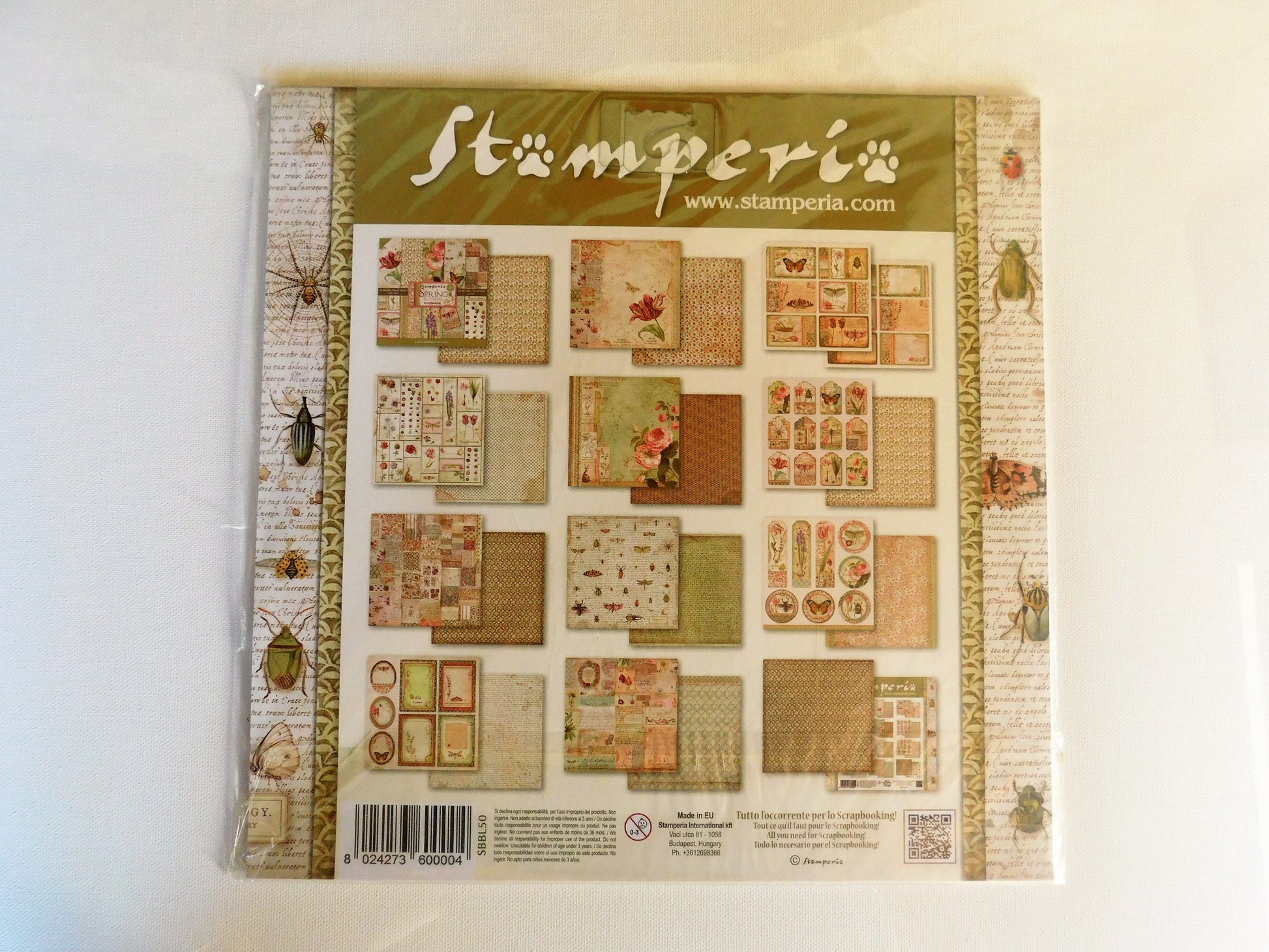 A packaged craft scrapbook paper set from Stamperia, featuring various vintage-style paper sheets with insect and retro designs, sealed in plastic packaging.
